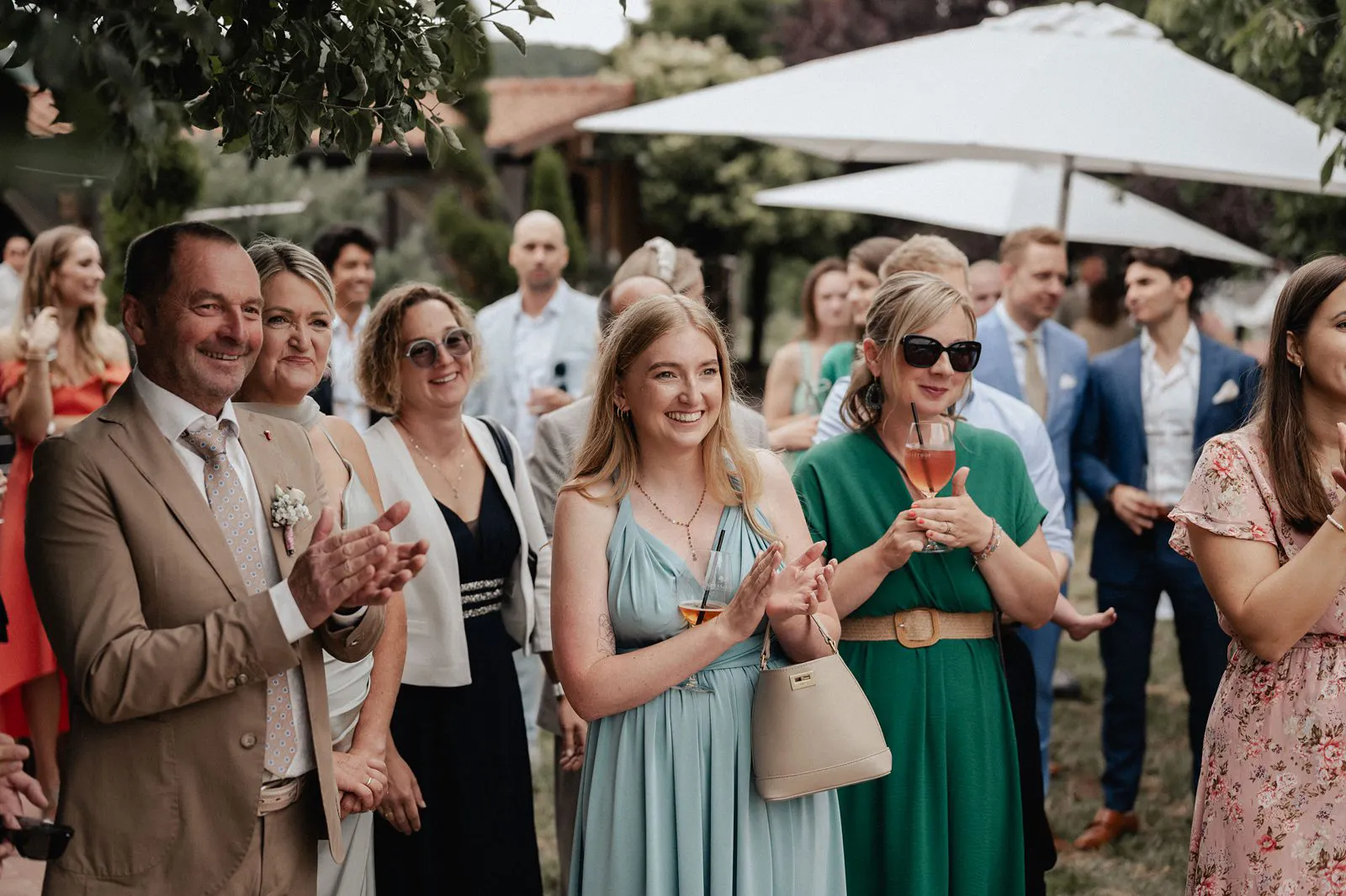 Gäste applaudieren und lächeln beim Sektempfang im Garten – Spessarthof, Aura im Sinngrund (nahe Gemünden am Main, Bayern).